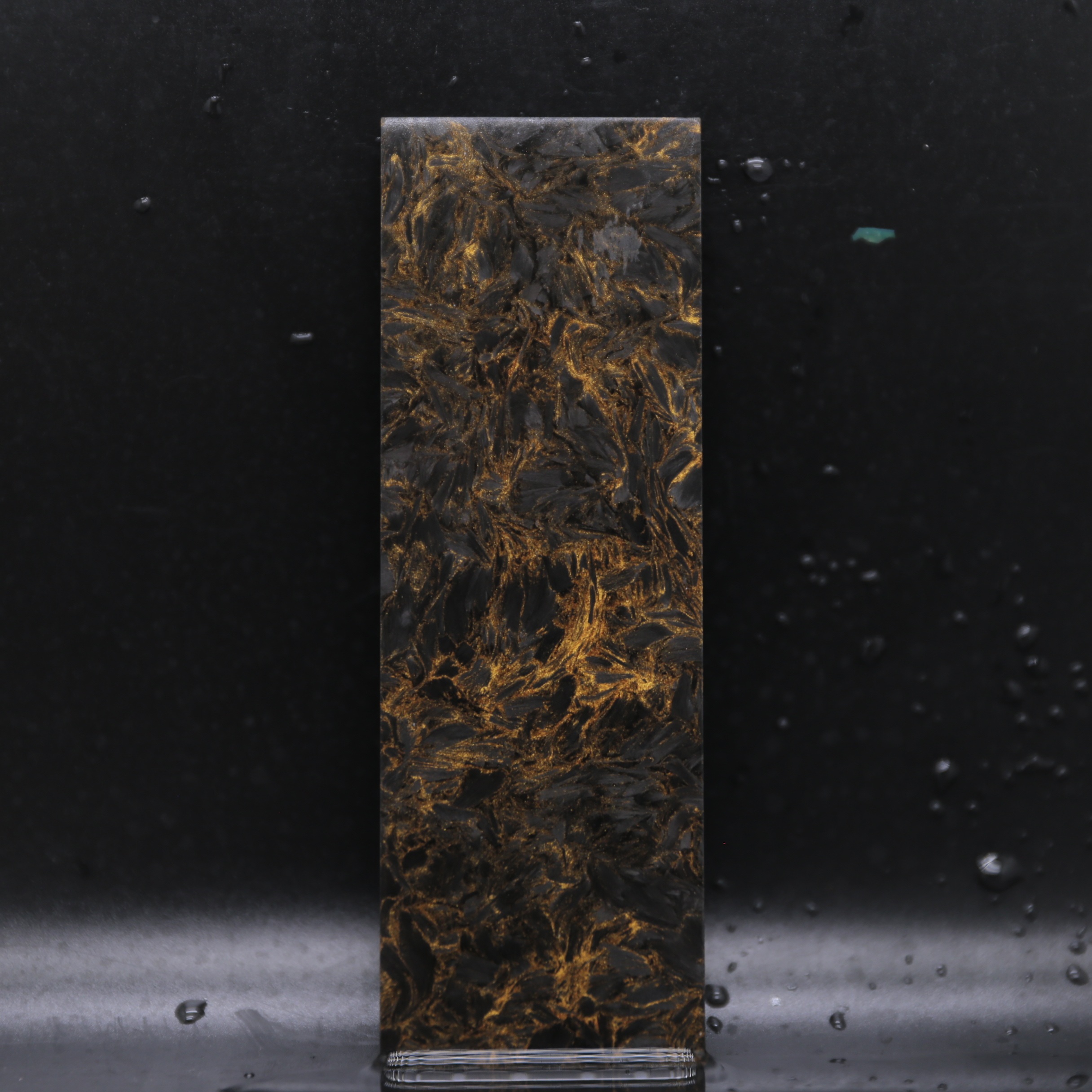 Obsidian Gold Collection forged carbon composite tube and rod stock material with black and gold metallic highlights for luxury products.