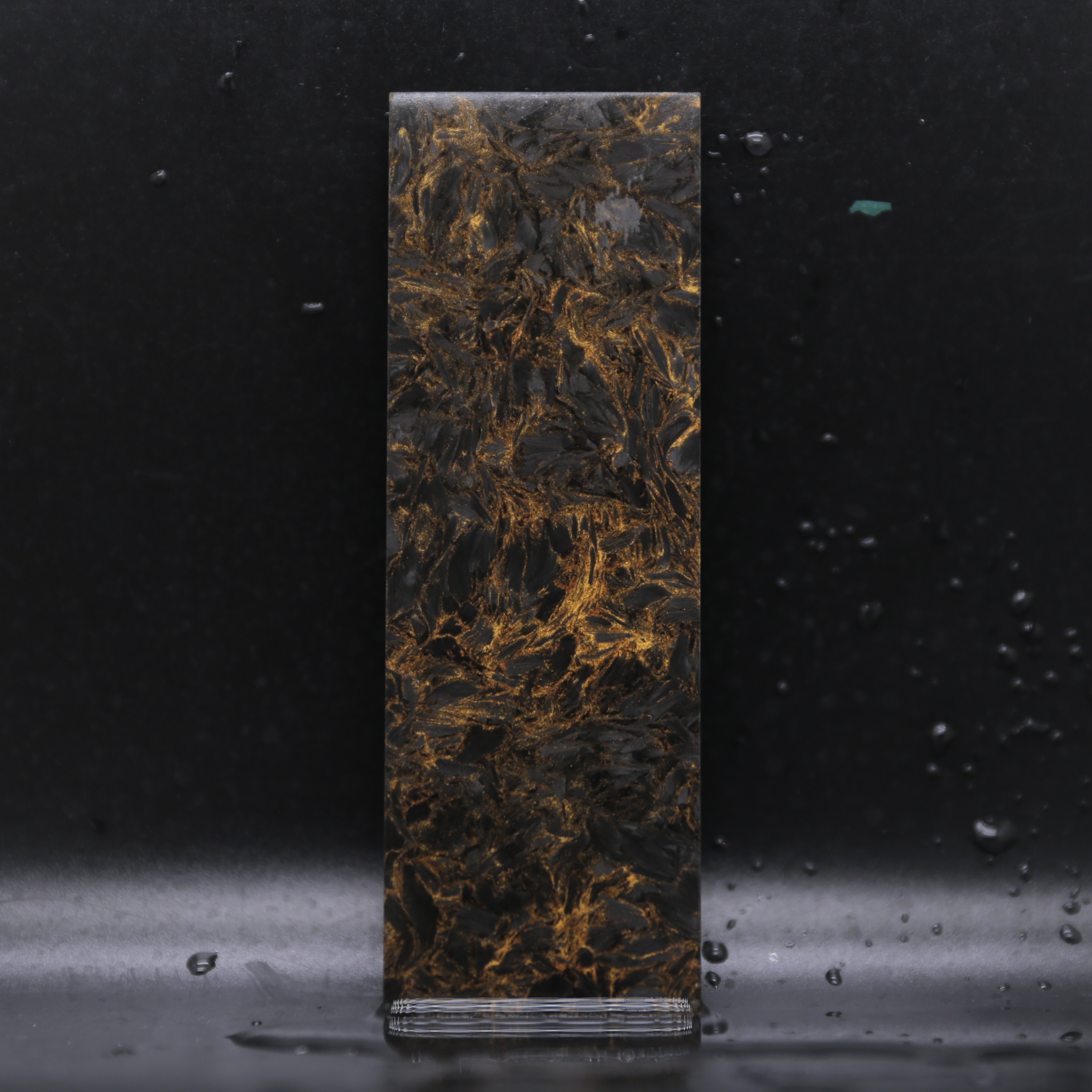 Obsidian Gold Collection forged carbon composite material with black and gold metallic highlights for luxury products.